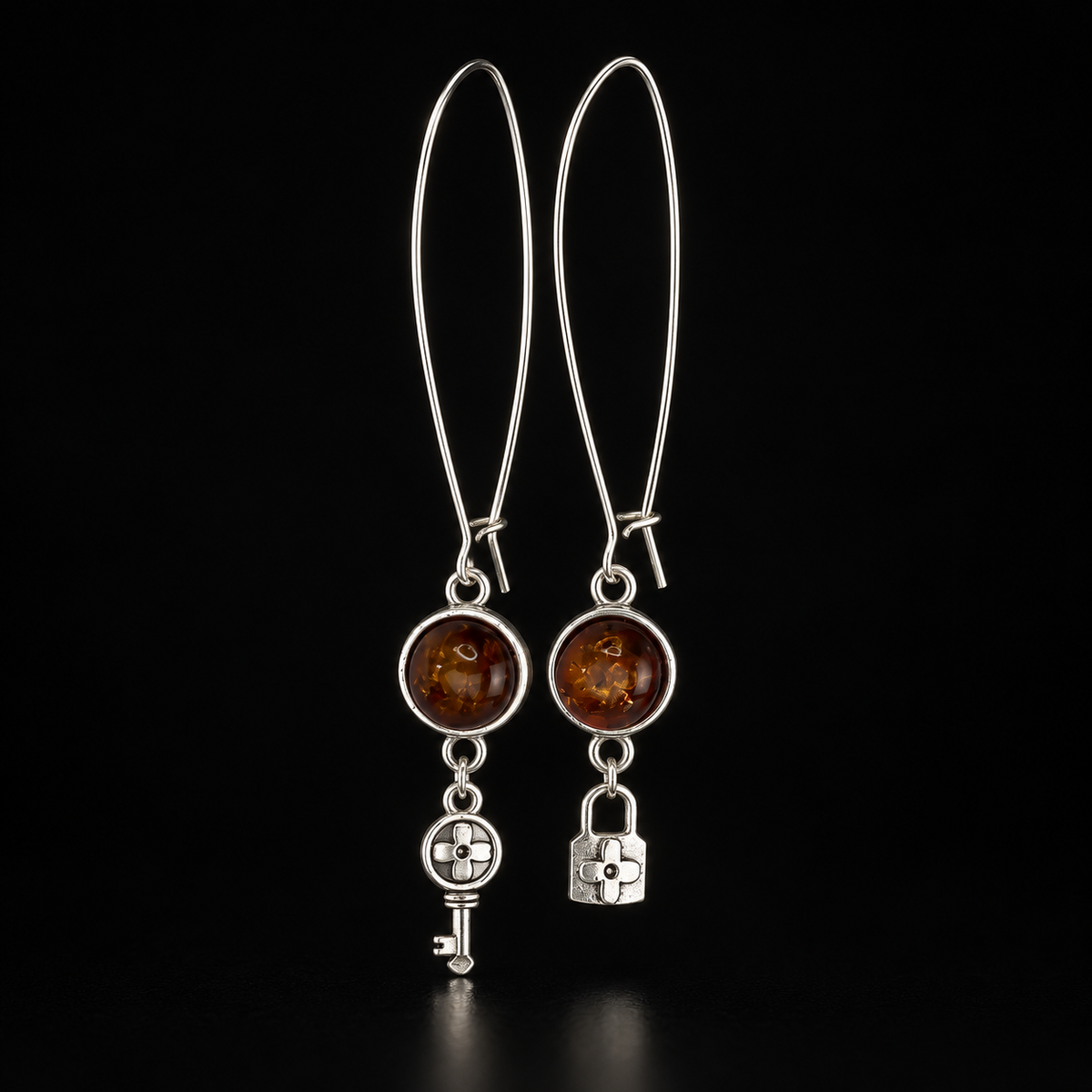 KIZIMA cognac amber key and lock earrings with elongated silver-tone wire hooks against black.