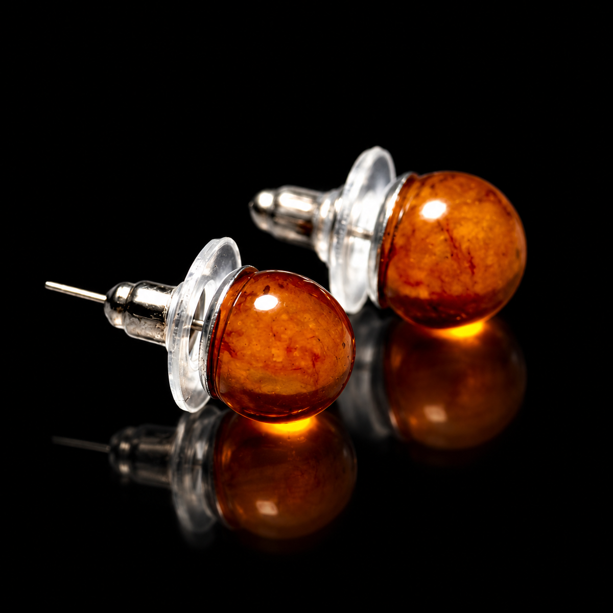 KIZIMA cognac Baltic amber stud earring pair with clear disk backs on a black studio background