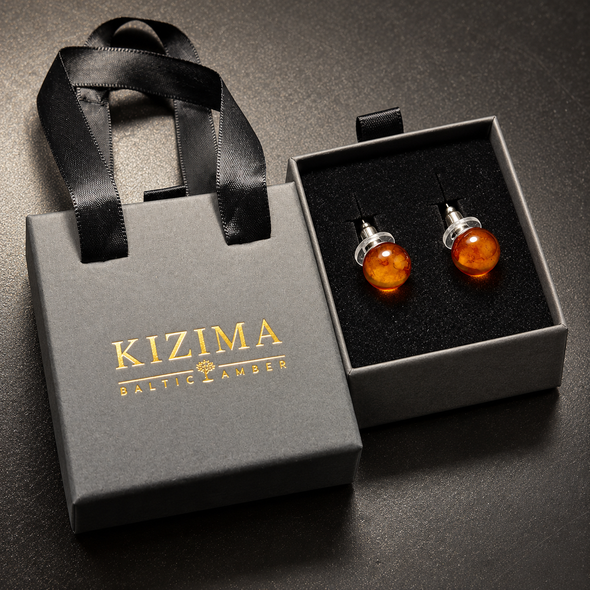 KIZIMA cognac Baltic amber stud earring pair presented in the signature charcoal gray drawer gift box with black ribbons and gold logo, SKU 662987478892