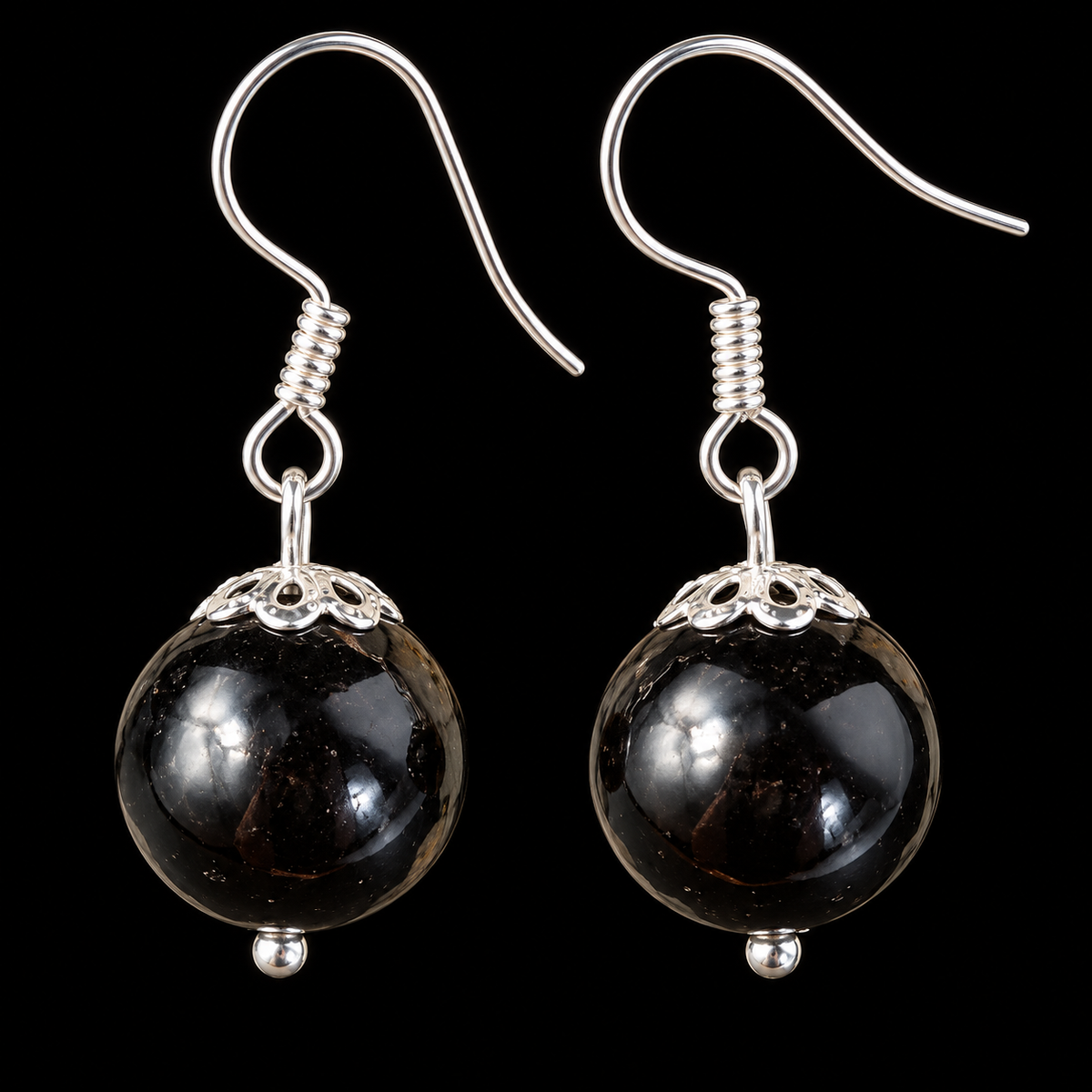 KIZIMA black Baltic amber sphere earrings with silver-tone fishhooks and filigree caps on a black studio background