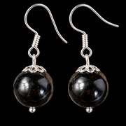 KIZIMA black Baltic amber sphere earrings with silver-tone fishhooks and filigree caps on a black studio background