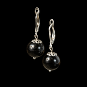 KIZIMA black Baltic amber sphere earrings with silver-tone leverbacks and filigree caps on a black studio background