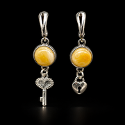 KIZIMA yellow amber key and heart-lock earring pair with silver-tone leverbacks on a black studio background.