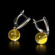 KIZIMA transparent honey-yellow amber sun ball earrings with silver-tone lock clasps, black studio view, SKU 662987479011.