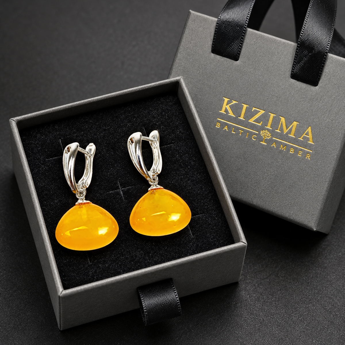 KIZIMA honey-yellow amber rounded drop earrings with silver leverbacks presented in the gray KIZIMA Baltic Amber gift box.