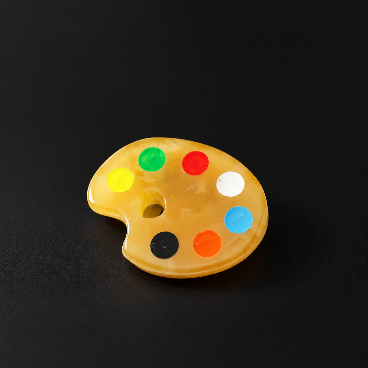 KIZIMA Baltic amber artist palette brooch with seven colored circles on black background.