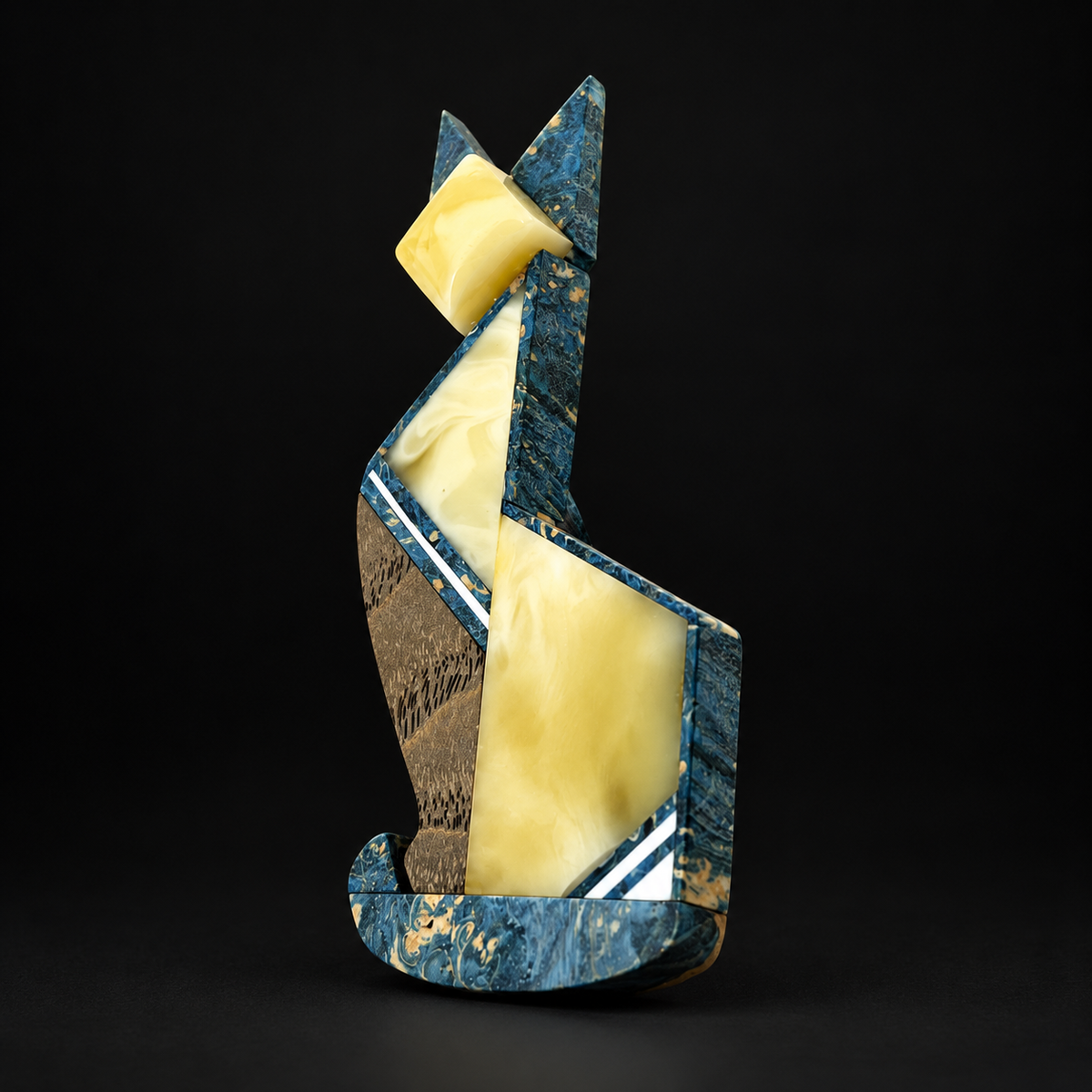 Angular cat brooch showing amber panels, wood grain and white diagonal inlays against a black studio background.