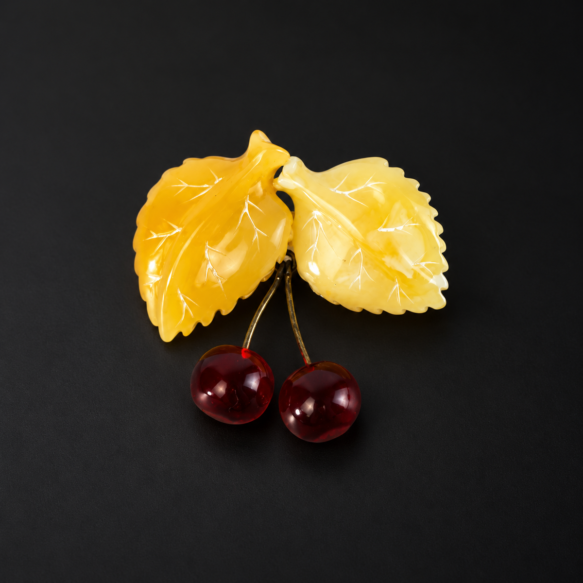 KIZIMA amber cherries brooch on black studio background.