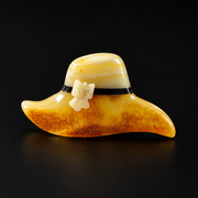 KIZIMA amber hat brooch with cream butterfly detail and orange amber brim on a black studio background.