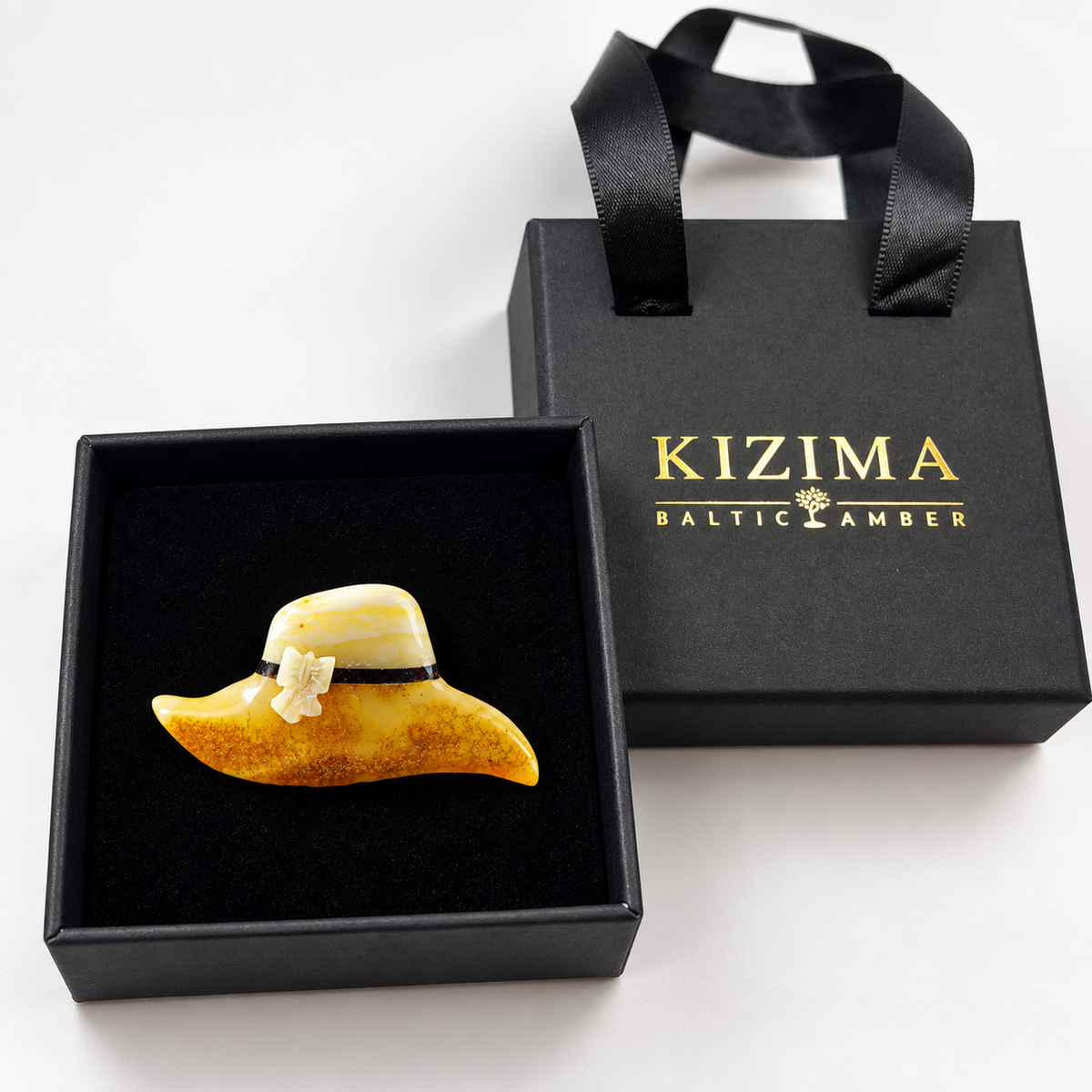 Amber hat brooch displayed in black KIZIMA gift packaging.