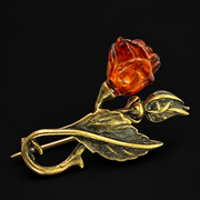 KIZIMA cognac amber rose brooch with antiqued brass-tone stem and leaf on a black background.