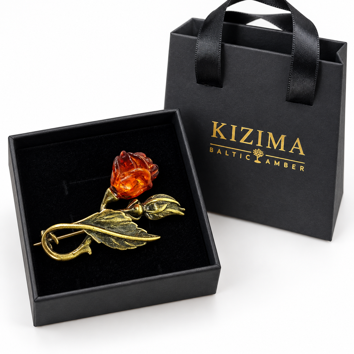 KIZIMA cognac amber rose brooch with antiqued brass-tone stem and leaf in a black KIZIMA gift box beside the matching bag.