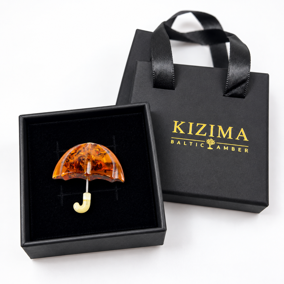 Small amber umbrella brooch displayed in black KIZIMA gift packaging.