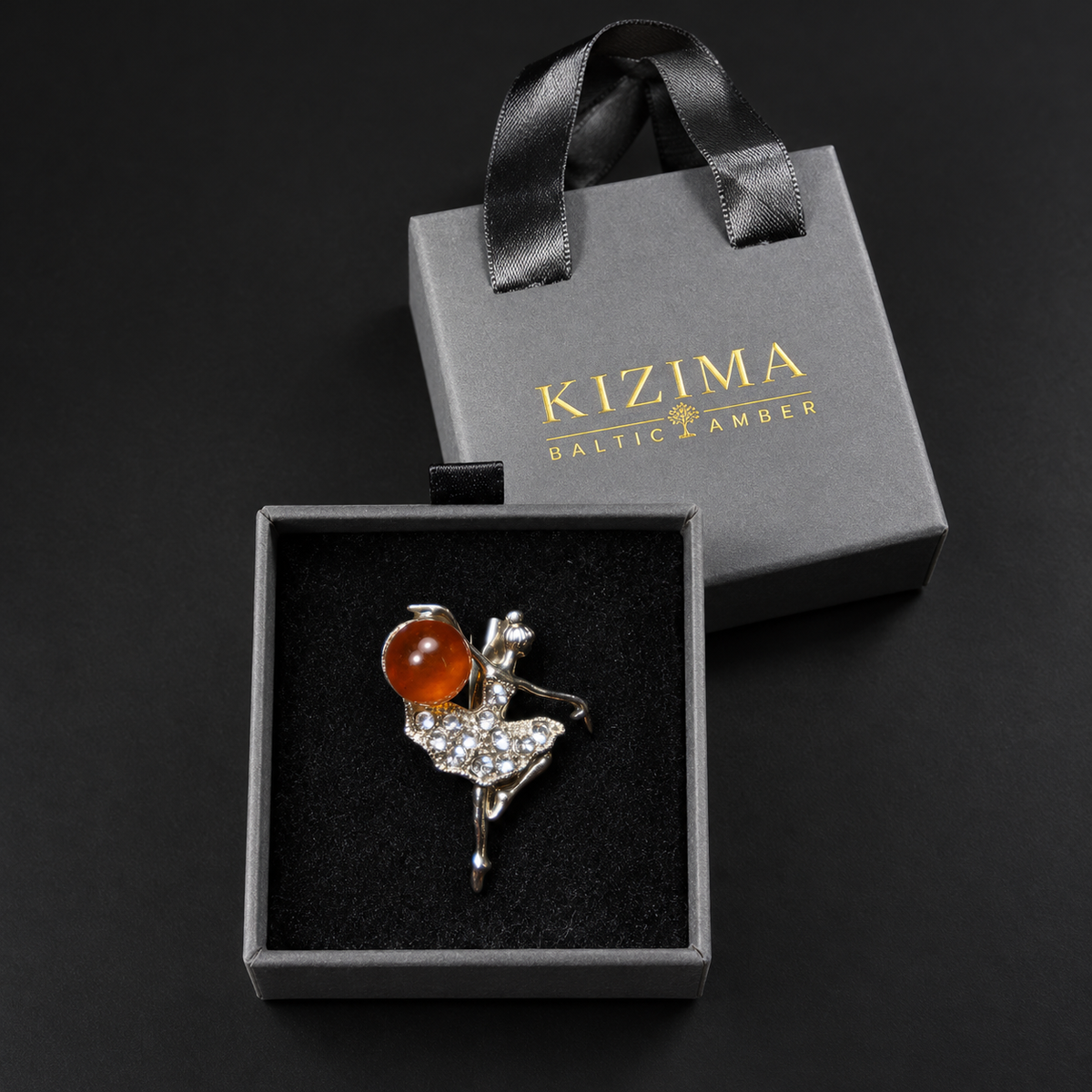 KIZIMA silver-tone Baltic amber ballerina brooch 20N0120-8 inside the charcoal-gray KIZIMA velvet-lined drawer gift box beside its ribbon-handled outer sleeve