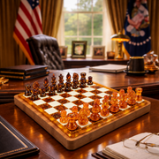 KIZIMA honey and cognac Baltic amber chess set on an inlaid wood board, diagonal side view on a presidential-style office desk with American flag.