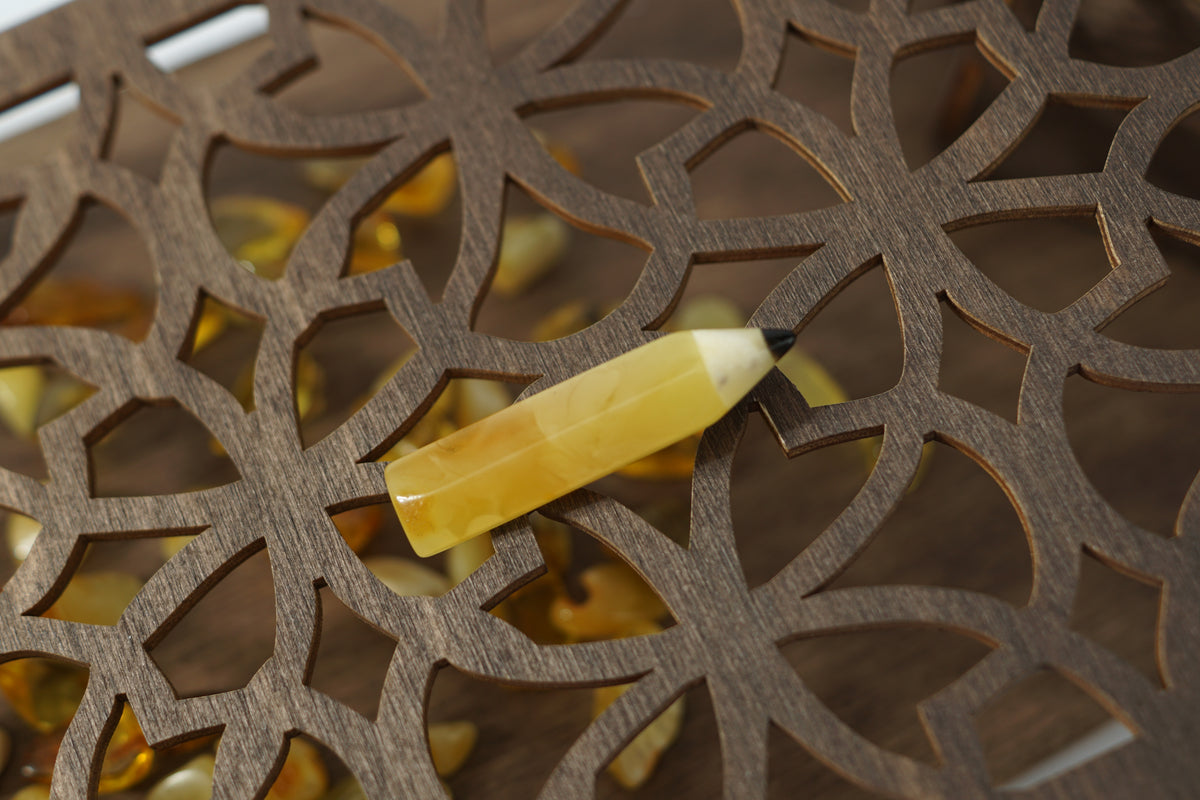 Faceted yellow amber pencil brooch on a carved wooden pattern; a graduation gift for a design student.