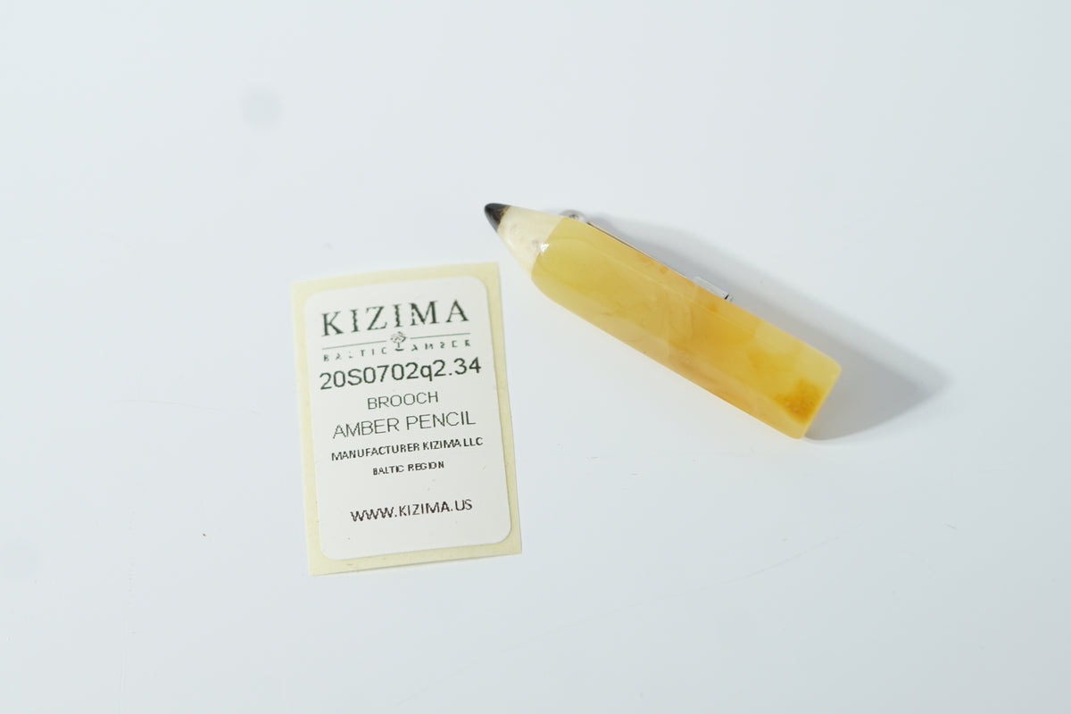 Yellow amber pencil brooch beside its KIZIMA product label on a pale surface; an end-of-year thank-you gift for a teacher.