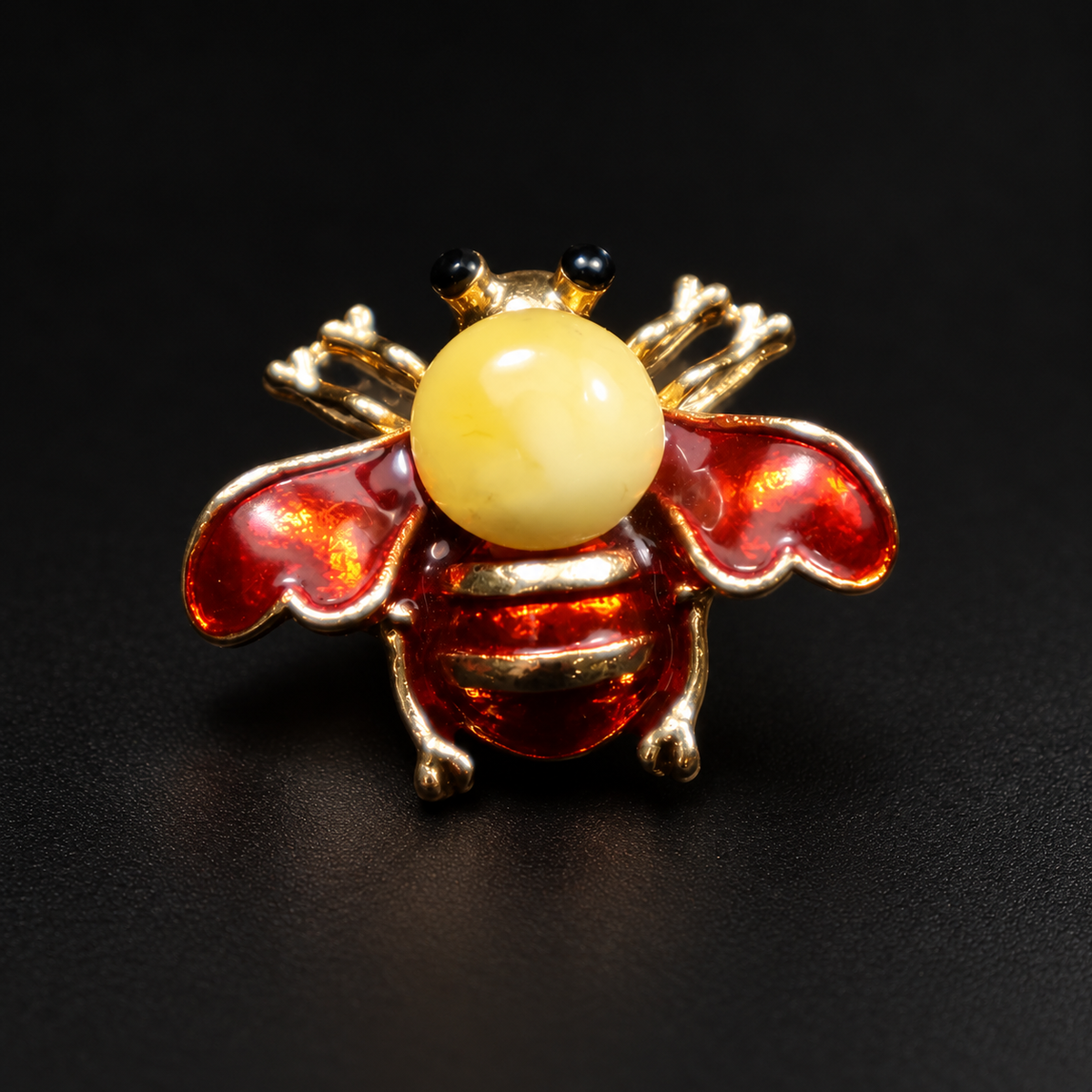 KIZIMA red enamel and opaque pale-yellow Baltic amber bee brooch 20-305Q5-3-3-2 on a black studio background.