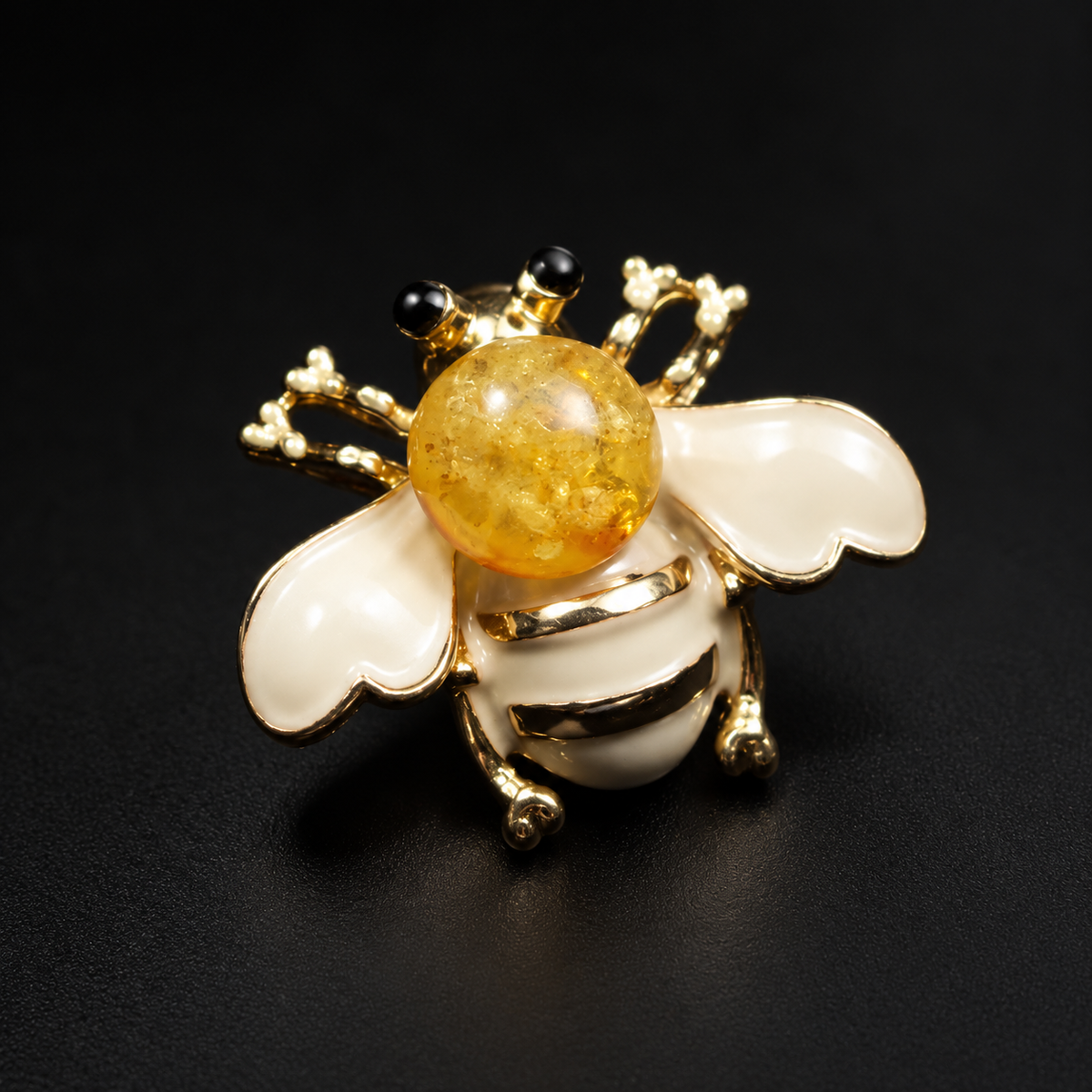 KIZIMA cream-white enamel and honey Baltic amber bee brooch 20-307Q5-3-3-2 on a black studio background.