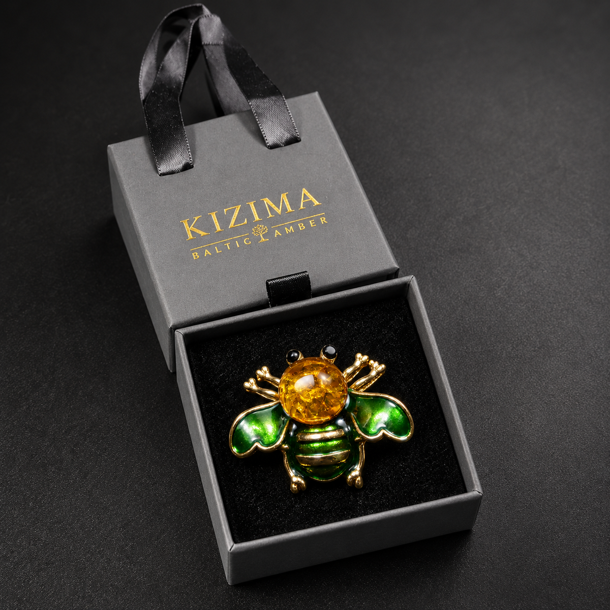 KIZIMA green enamel and golden Baltic amber bee brooch 20-310Q5-3-3-2 in its charcoal-gray KIZIMA velvet-lined drawer gift box.