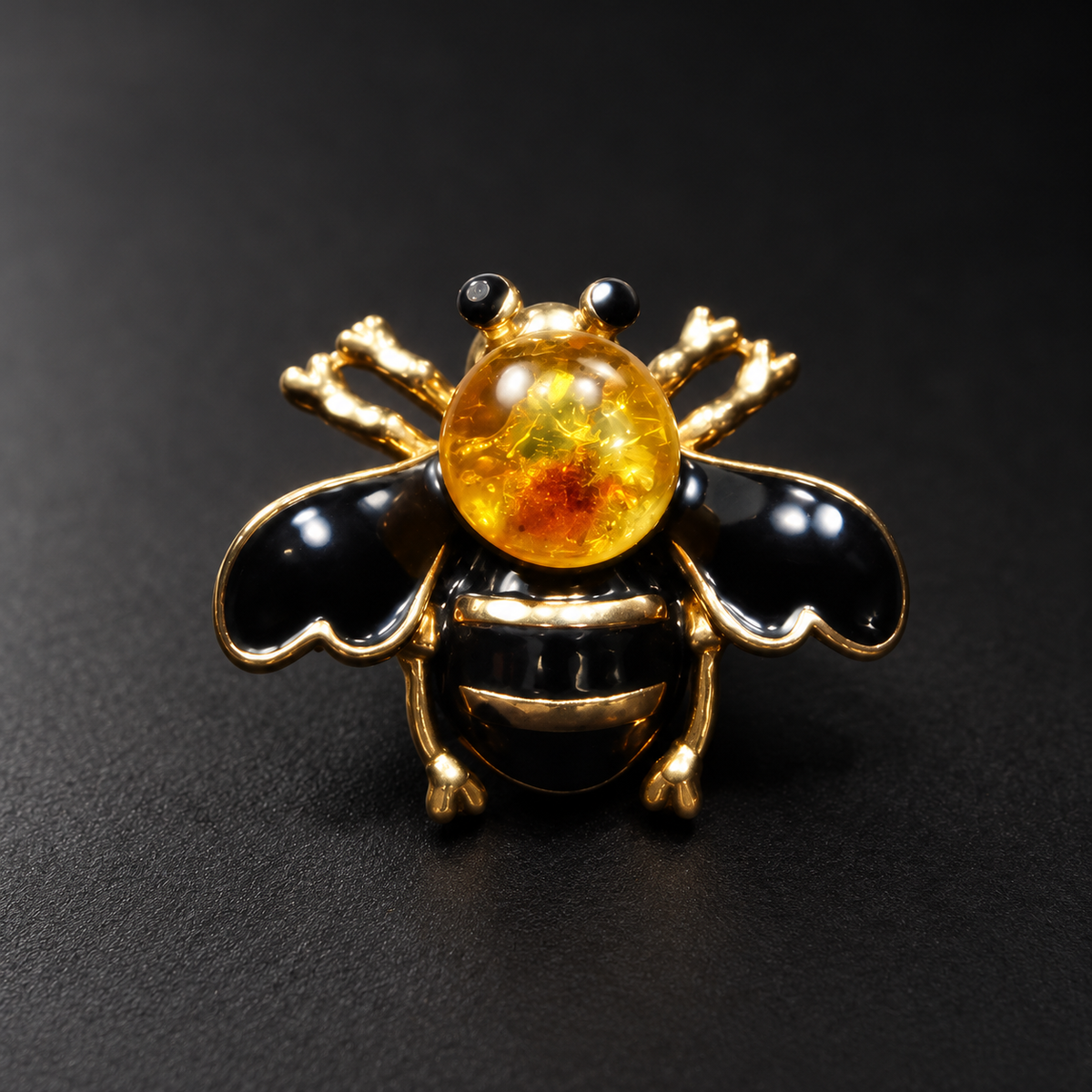 KIZIMA black enamel bee brooch 20N0120-38 with round Baltic amber on a black studio background.