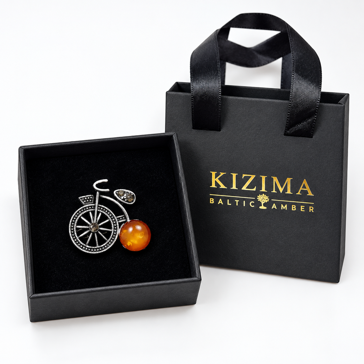 KIZIMA silver-tone bicycle brooch with cloudy honey-orange Baltic amber wheel in actual black KIZIMA gift packaging.