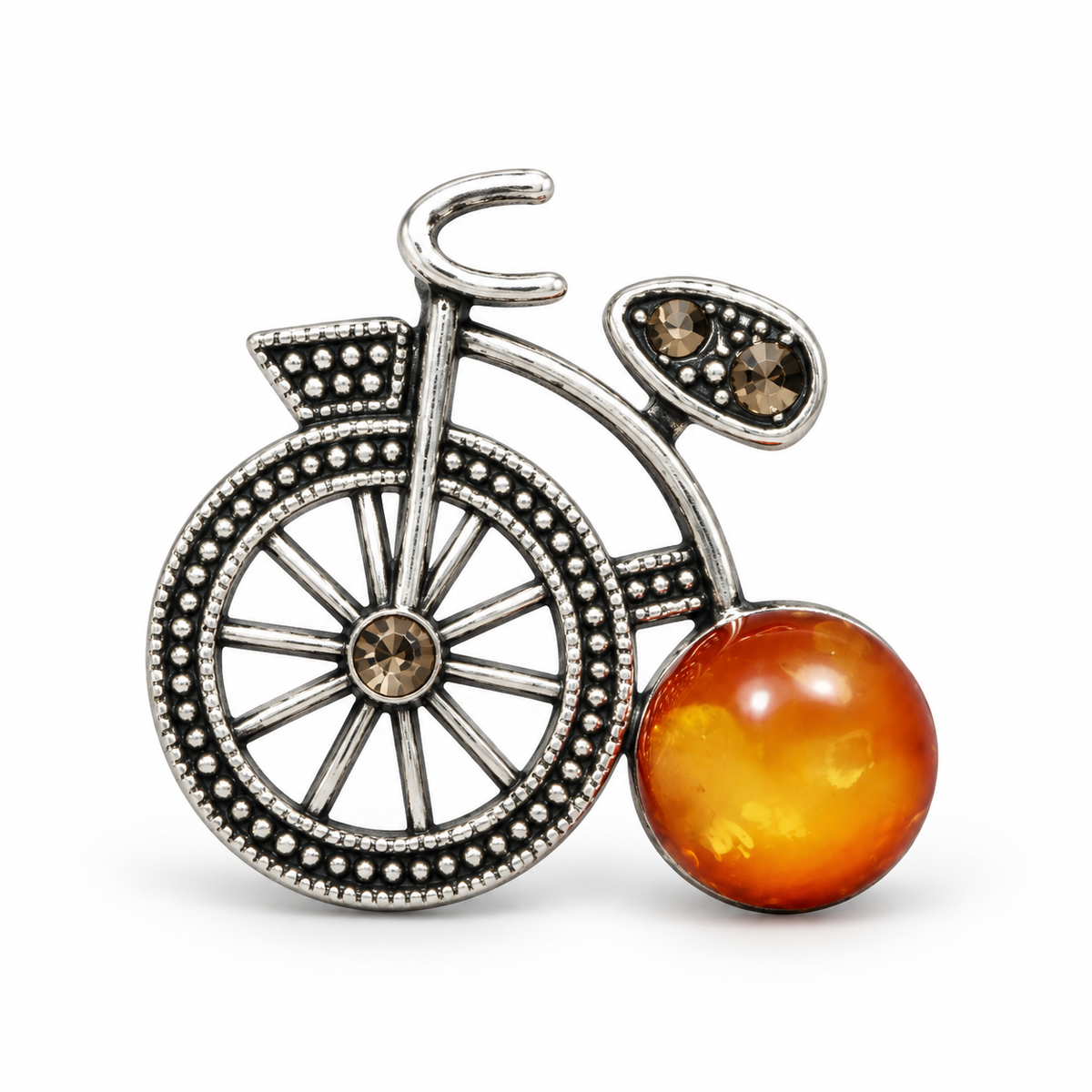 KIZIMA silver-tone bicycle brooch with cloudy honey-orange Baltic amber wheel on white studio background.