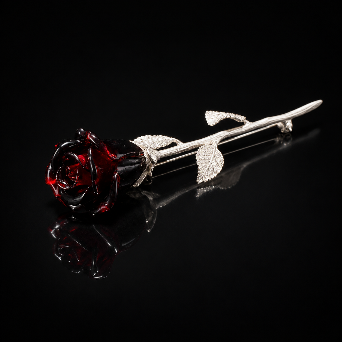 KIZIMA near-black burgundy Baltic amber rose brooch with silver-tone stem and three leaves on black studio background.