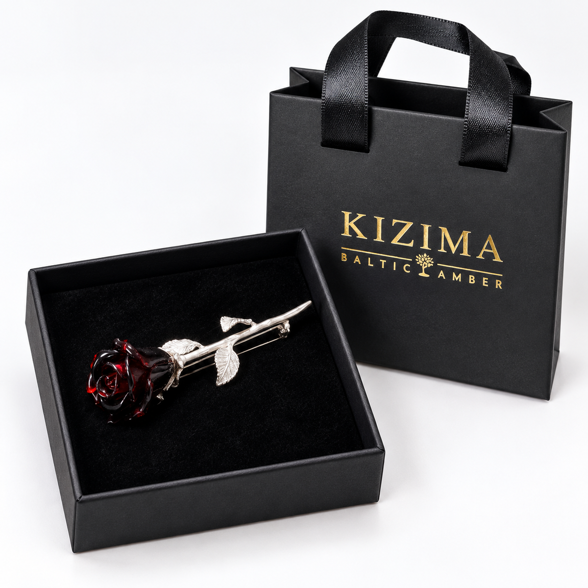 KIZIMA near-black burgundy Baltic amber rose brooch with silver-tone stem and three leaves in actual black KIZIMA gift packaging.