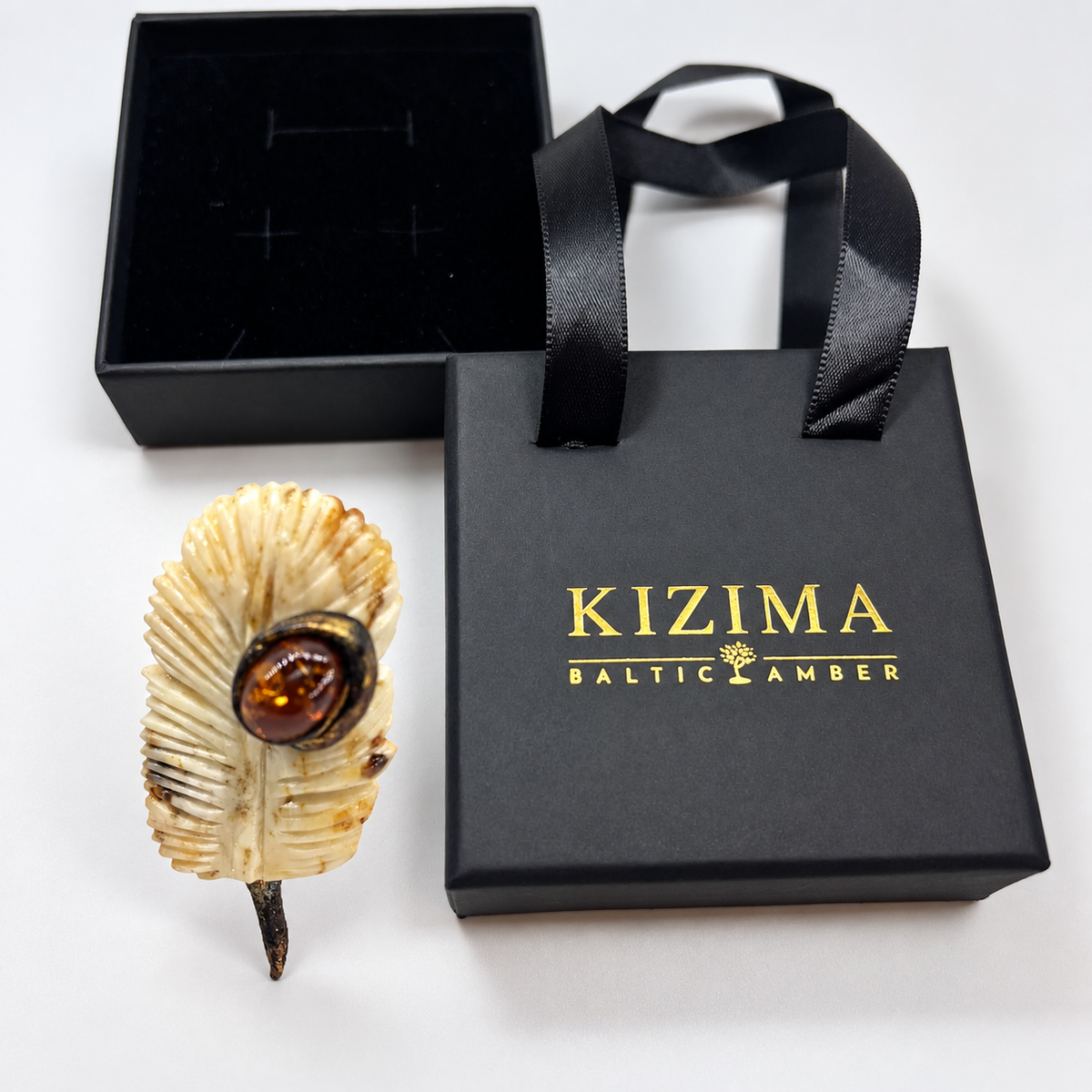 KIZIMA amber brooch 20E2500q5.61, beside black KIZIMA packaging.