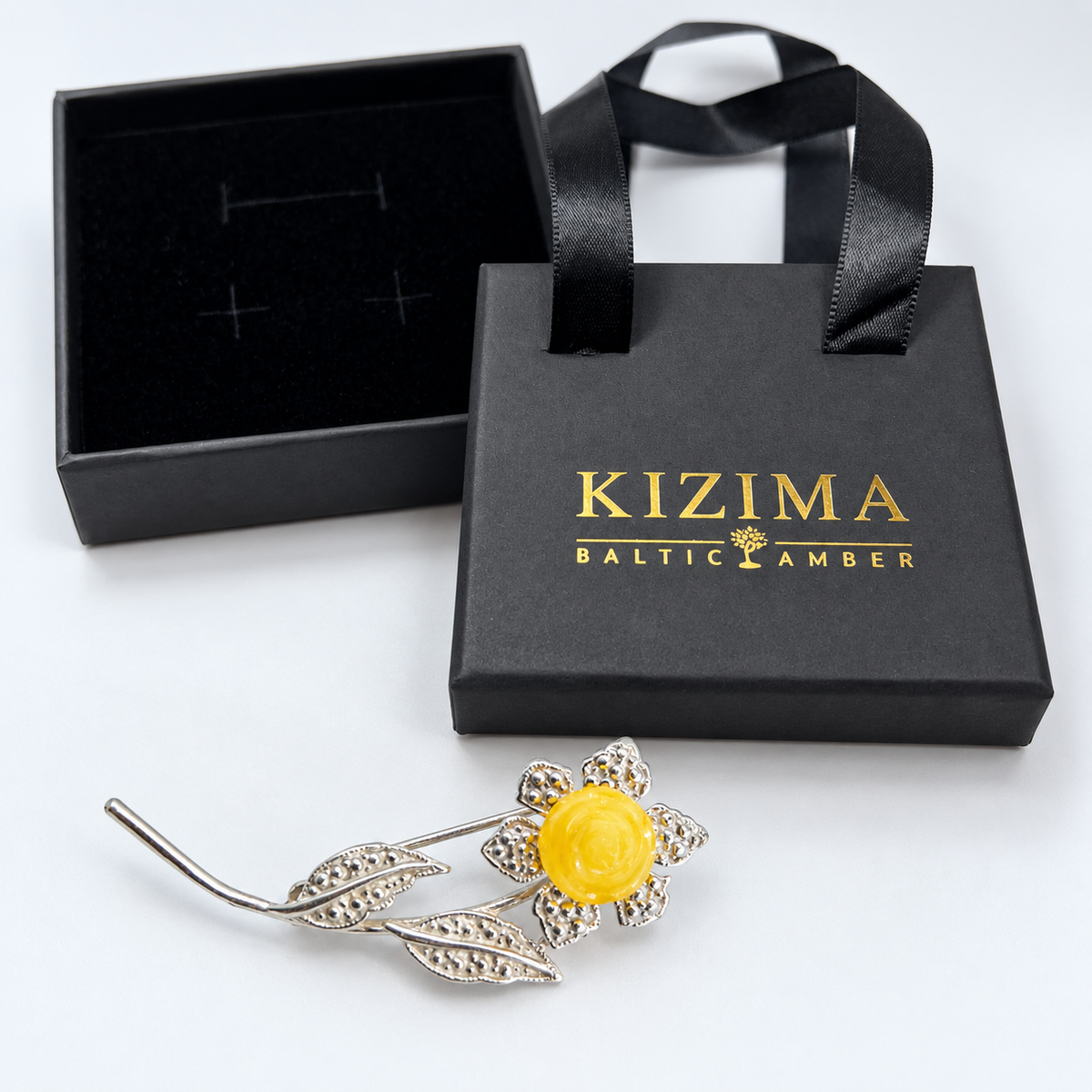 KIZIMA Baltic amber brooch 20G0125q3-1 beside authentic black KIZIMA gift packaging.
