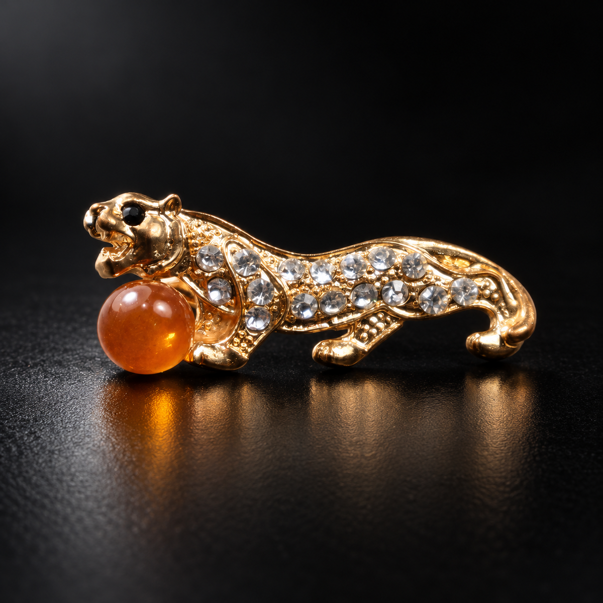 KIZIMA gold-tone tiger brooch 20N0120-19 with honey-orange Baltic amber on a black studio background.