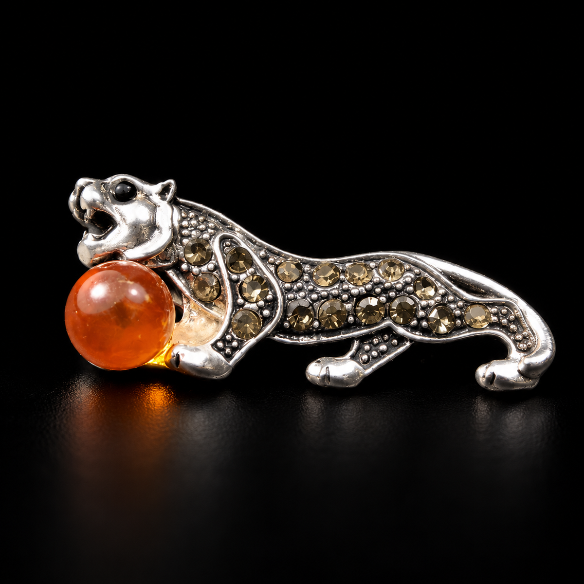 KIZIMA silver-tone tiger brooch 20N0120-20 with honey-orange Baltic amber on a black studio background.