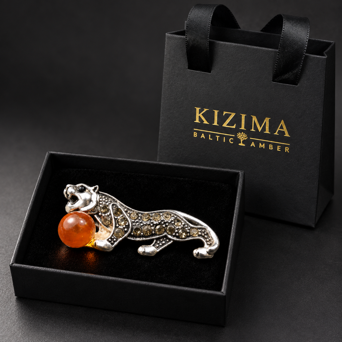 KIZIMA silver-tone tiger brooch 20N0120-20 with honey-orange Baltic amber in the real black velvet KIZIMA box beside the matching gift bag.