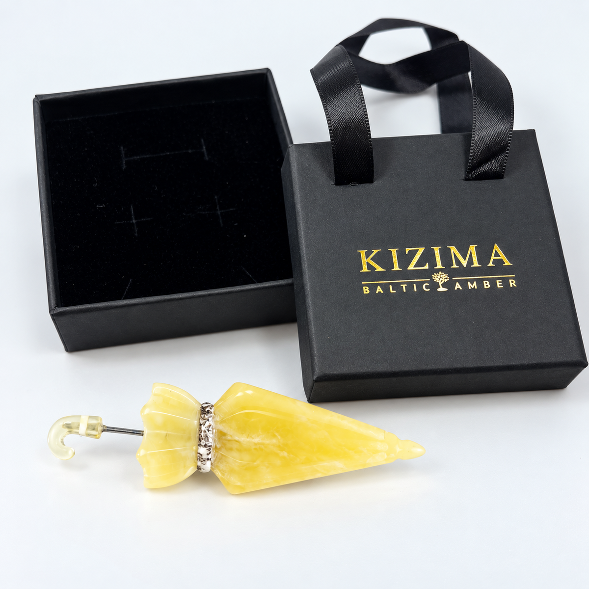 KIZIMA Baltic amber brooch 20S0846q2.82 beside authentic black KIZIMA gift packaging.