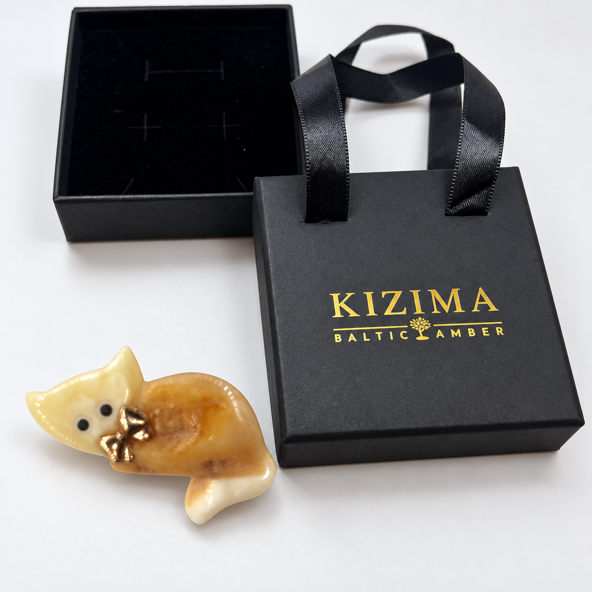 KIZIMA amber brooch 20S1245q4.15, beside black KIZIMA packaging.