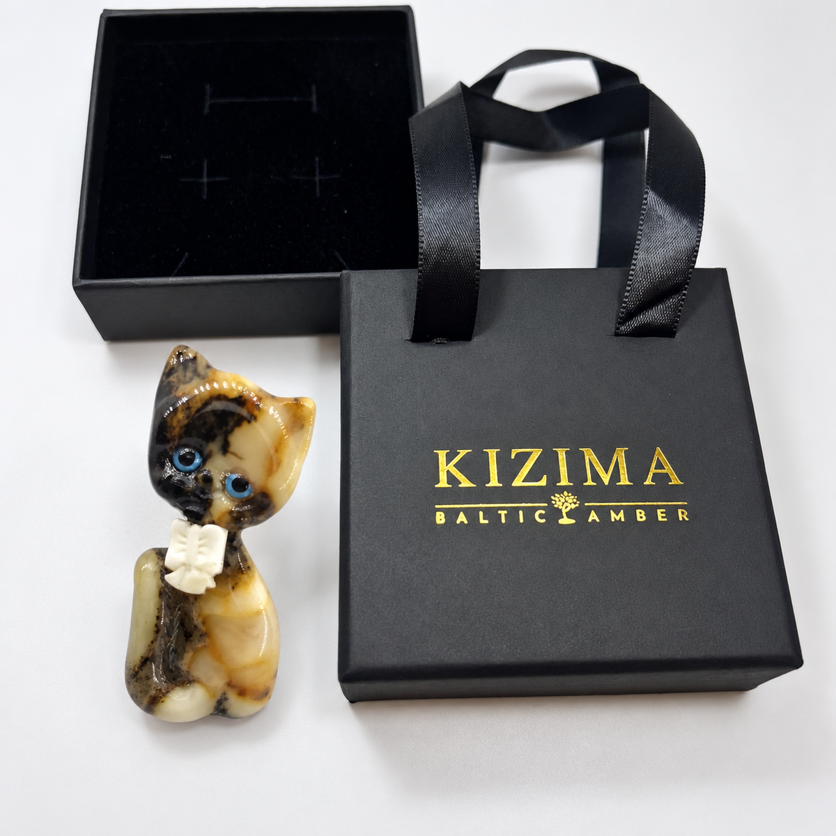 KIZIMA amber brooch 20S1251q4.17, beside black KIZIMA packaging.
