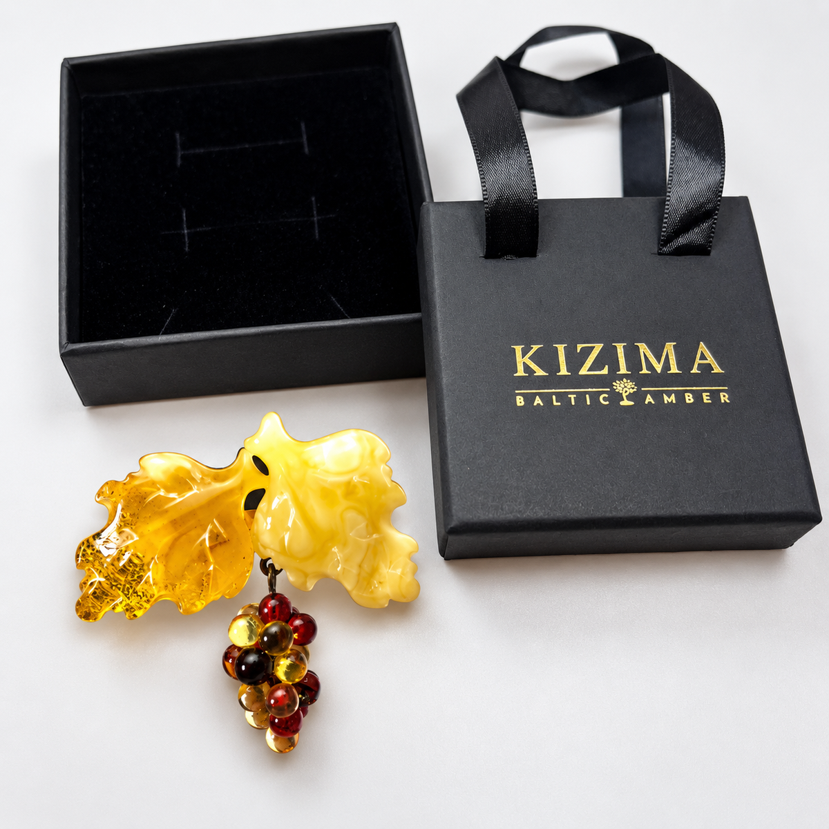 KIZIMA amber brooch 20S1650q5.50, beside black KIZIMA packaging.