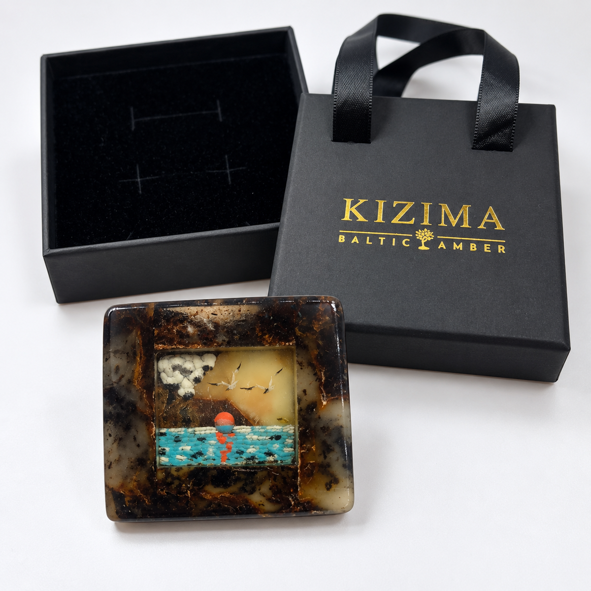 KIZIMA Baltic amber brooch 20S2832q9.44 beside authentic black KIZIMA gift packaging.
