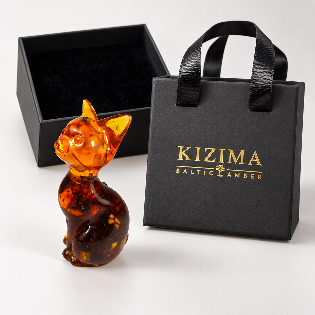 Slender amber cat with a honey-colored head and dark body with a black velvet-lined box and branded KIZIMA gift bag