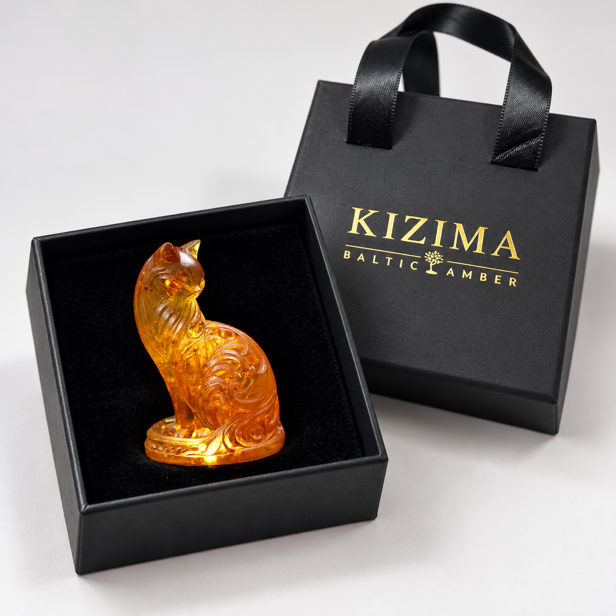 Ornate amber cat with flowing scrollwork on an oval base with a black velvet-lined box and branded KIZIMA gift bag