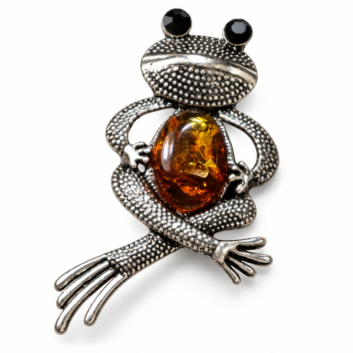 KIZIMA silver-tone seated frog brooch with black eyes and cognac Baltic amber belly on white studio background.