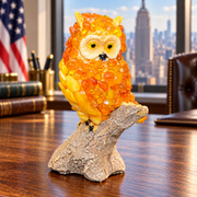 Made in USA natural Baltic amber golden-orange owl on a bark branch on an oak desk in an American office.