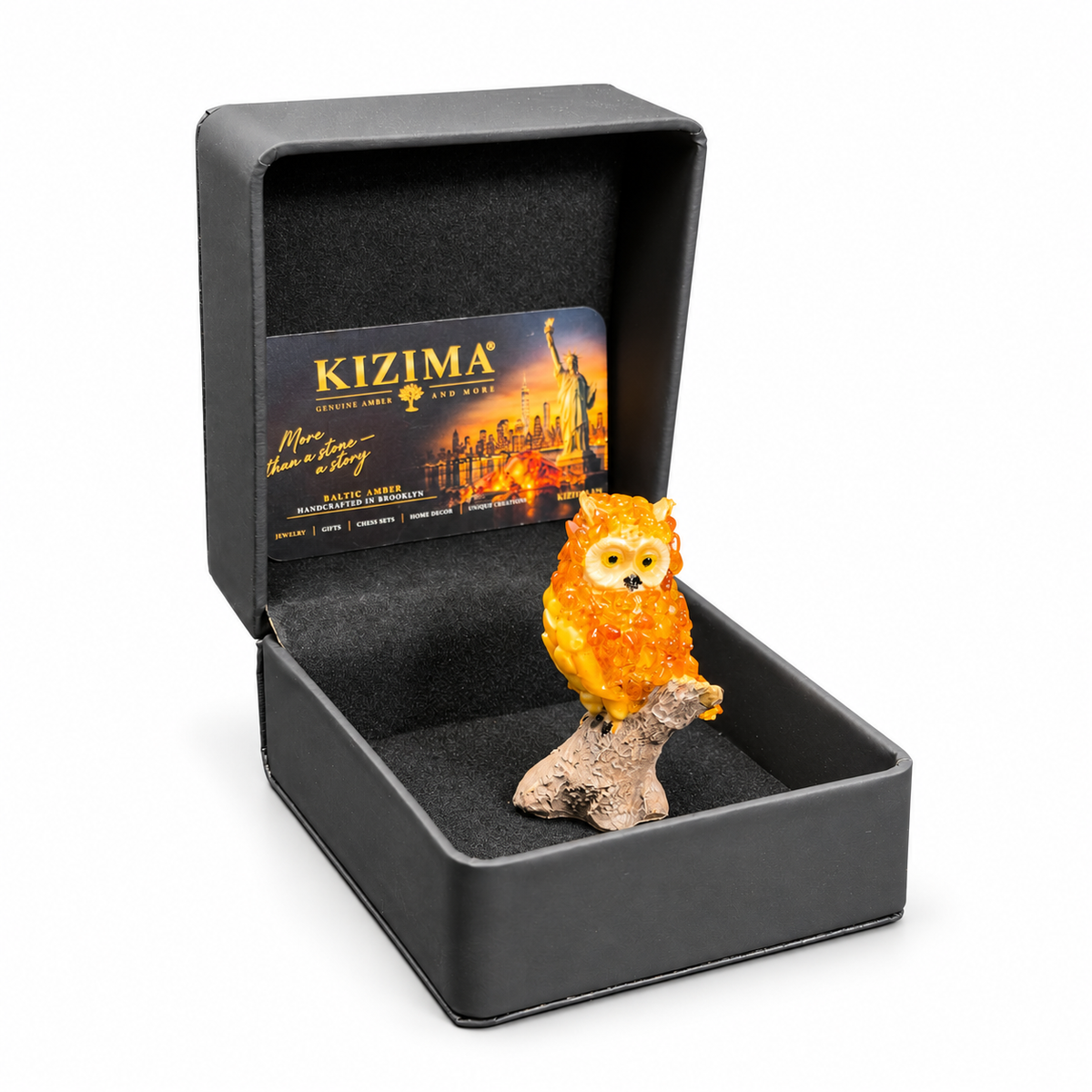 Golden-orange OWL24 owl figurine presented in the actual open black KIZIMA gift box on white
