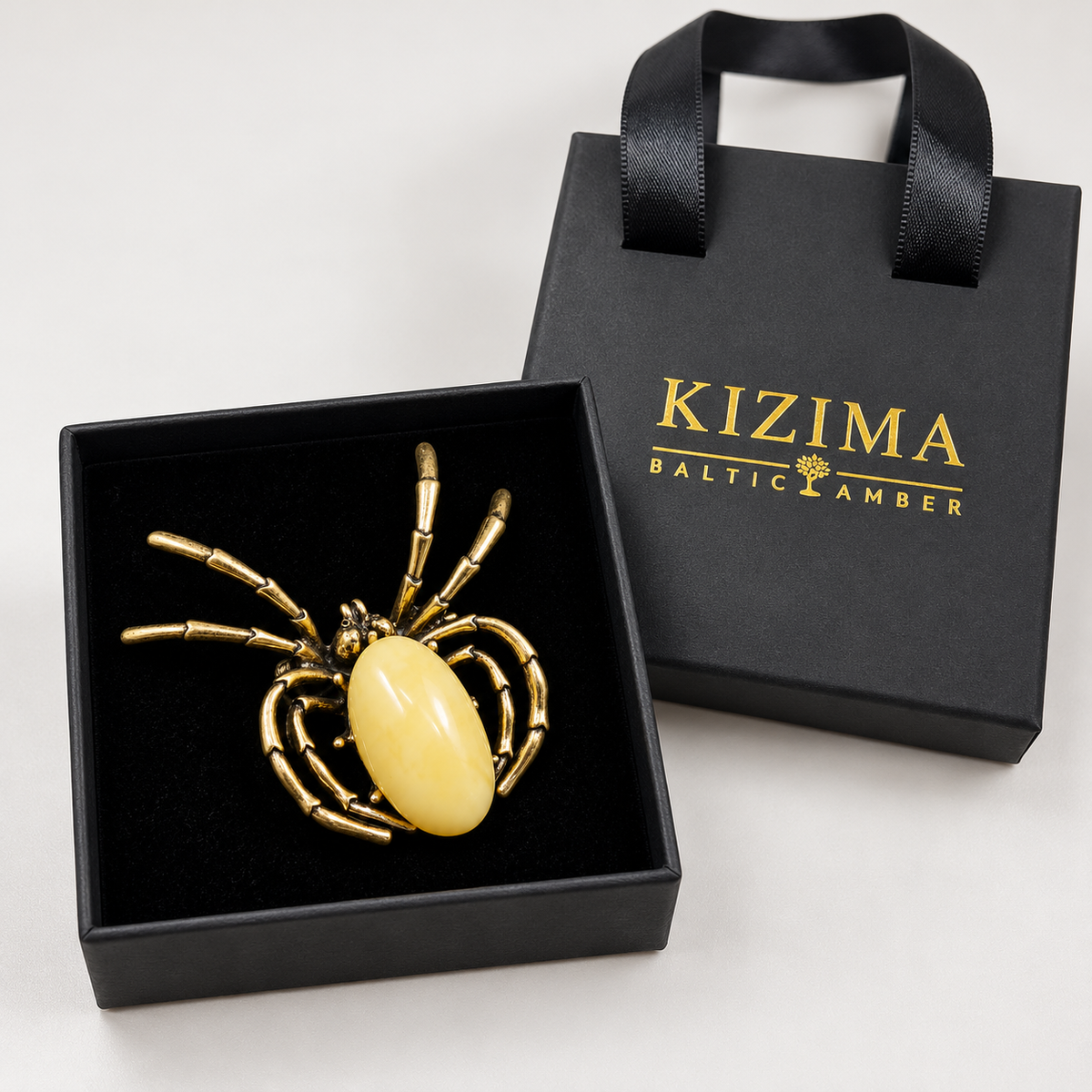 KIZIMA pale opaque yellow amber Gothic spider brooch 20-311Q19-6-6-2, with actual KIZIMA gift packaging.