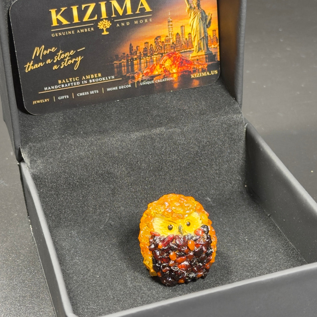 Original photo of the miniature owl figurine inside an open black KIZIMA presentation box