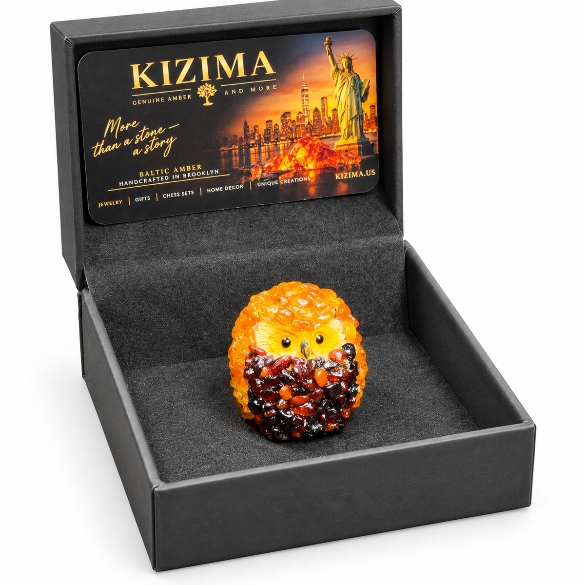 Small golden-orange owl figurine presented with an open black KIZIMA box