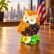 Made in USA natural Baltic amber mini owl on a green flower base on an oak desk with a Manhattan skyline.