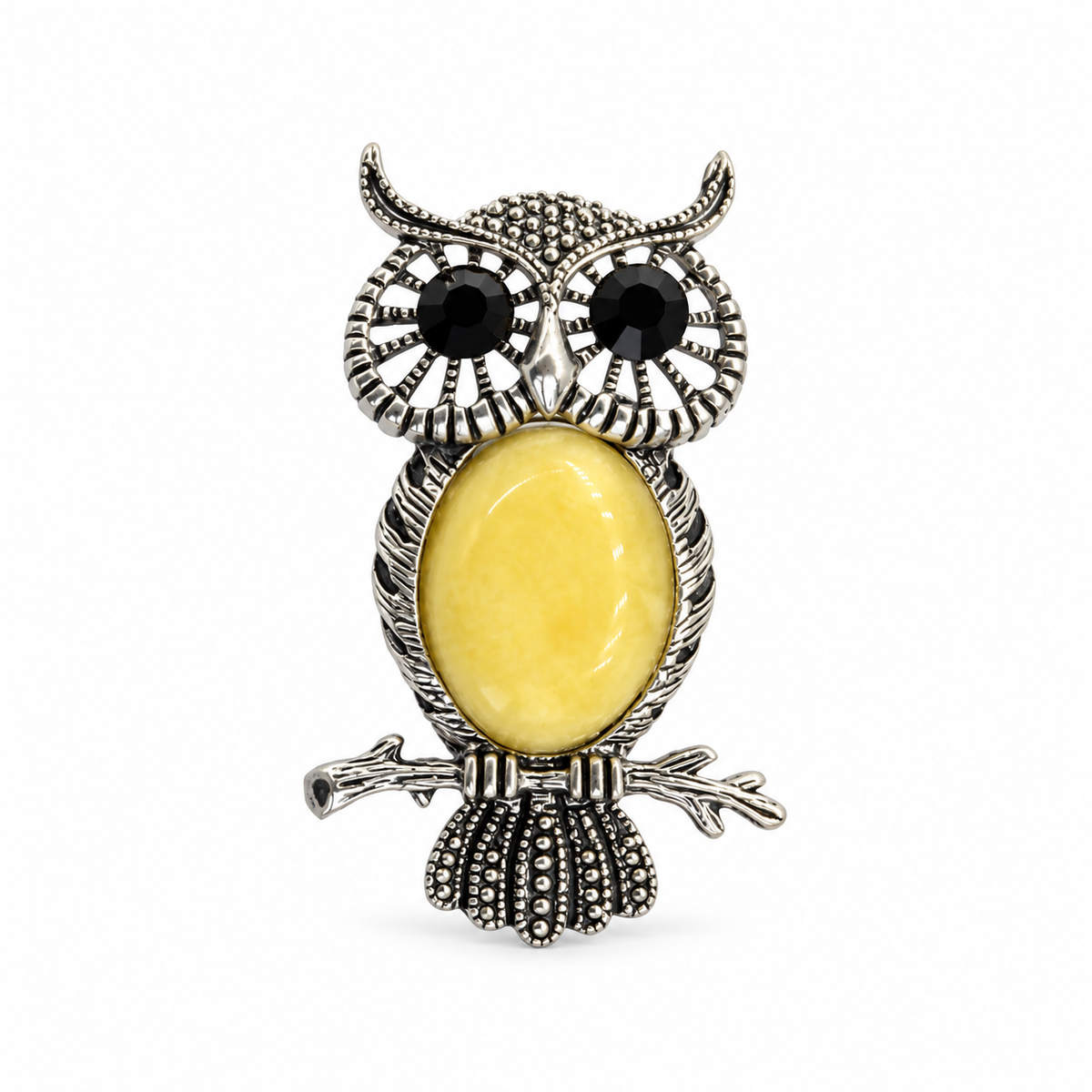 KIZIMA silver-tone owl brooch with black eyes and opaque pale-yellow Baltic amber belly on white studio background.