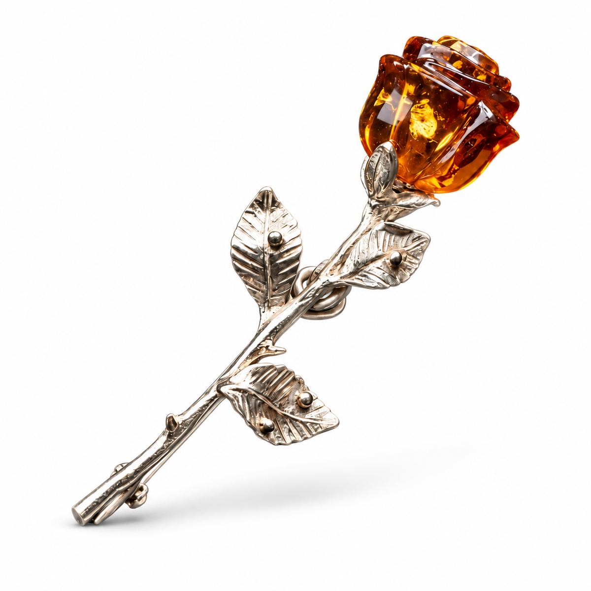 KIZIMA silver-tone rose brooch with a carved cognac Baltic amber bud and three veined leaves on a white studio background.